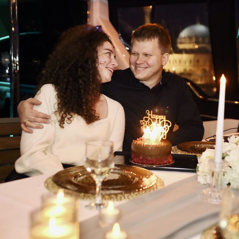 Couple with a birthday cake and candles at the table on board