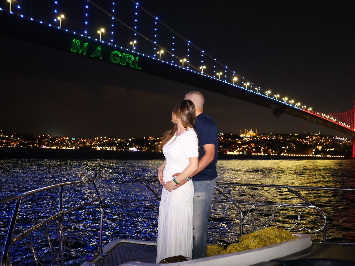 Werdende Eltern an Deck, an der Bosporus-Brücke die Laserschrift Im a girl