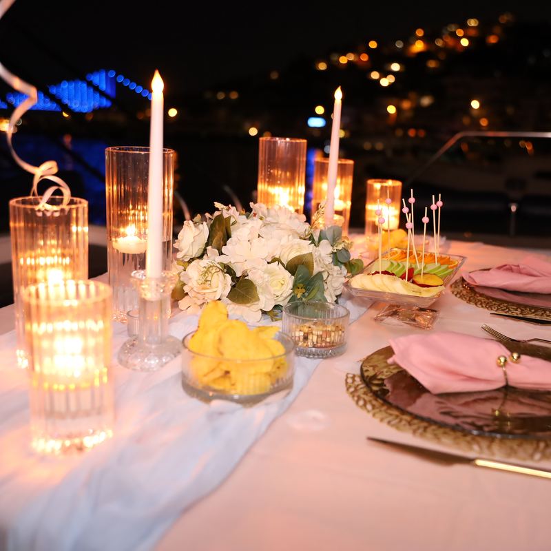 Gedeckter Tisch mit Kerzen, weißen Blumen und rosa Servietten