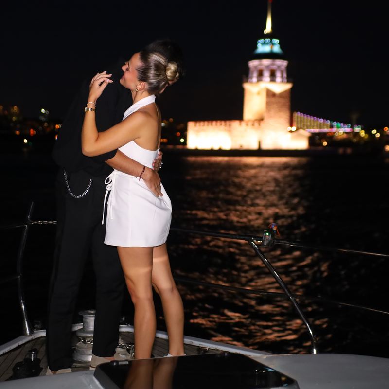 Embrace on deck in front of the lit Maiden's Tower at night