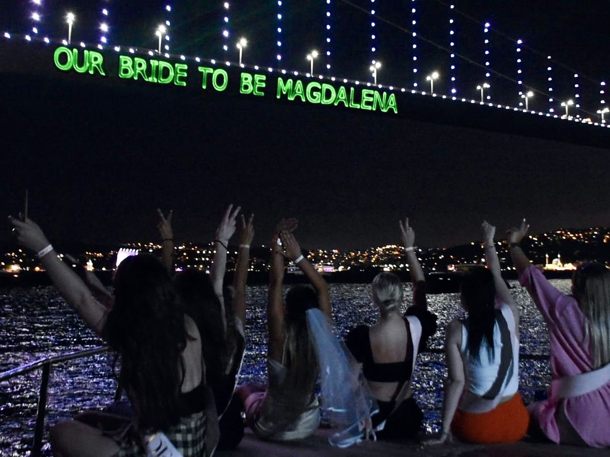 Freundinnen an Deck, über ihnen der Laserschriftzug an der Bosporus-Brücke
