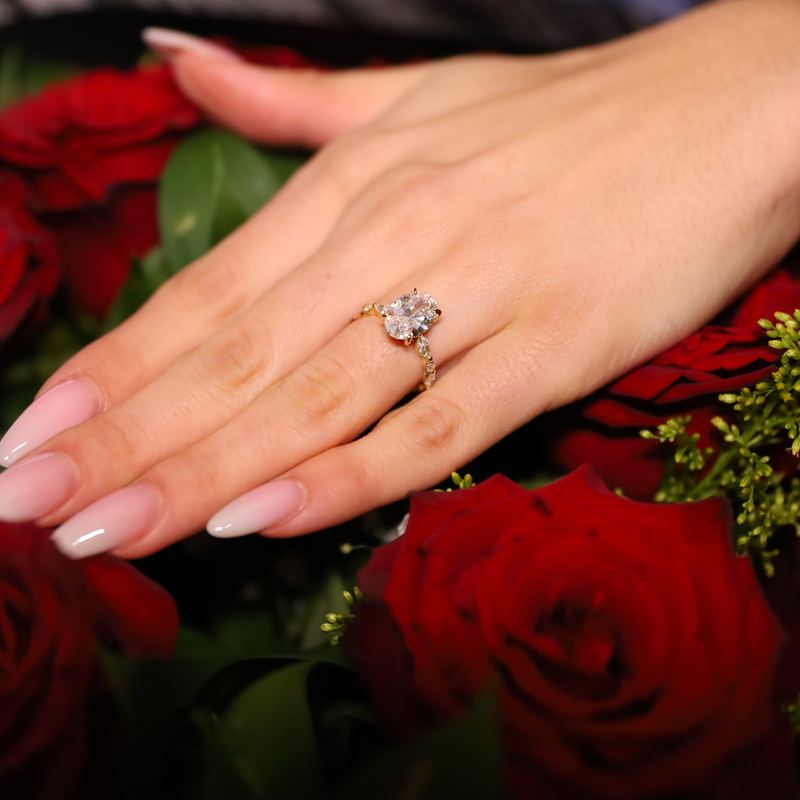 Engagement ring on a hand above red roses
