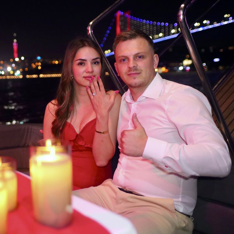 Couple with the ring in front of the night skyline