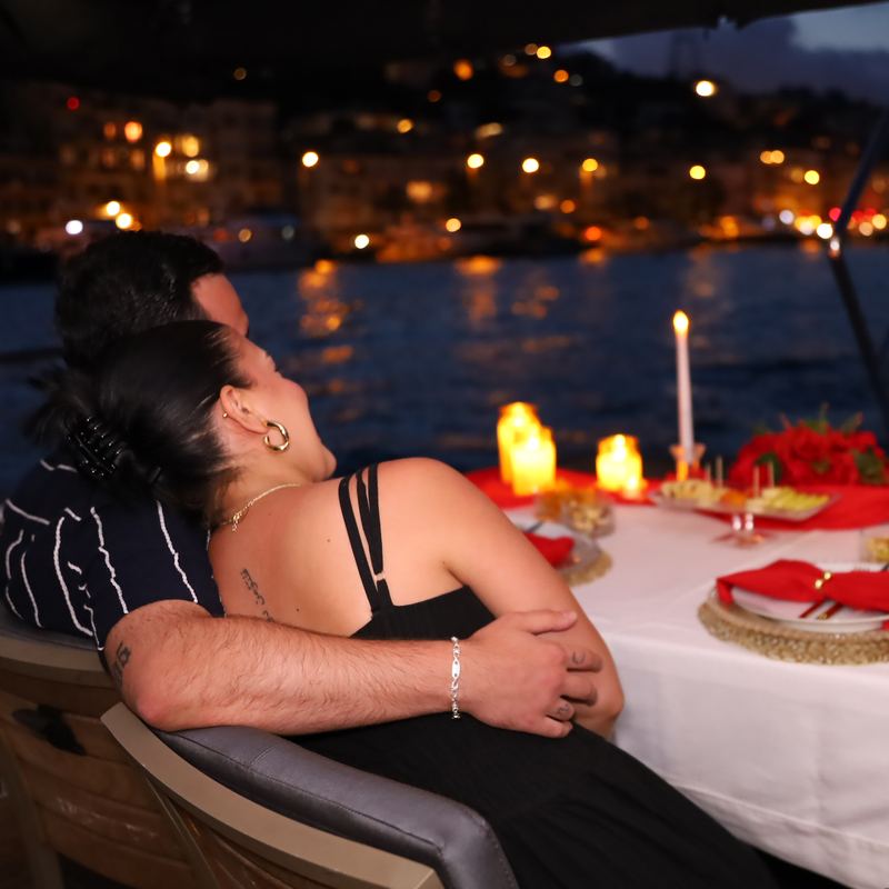 Couple at the table looking out at the lit shoreline