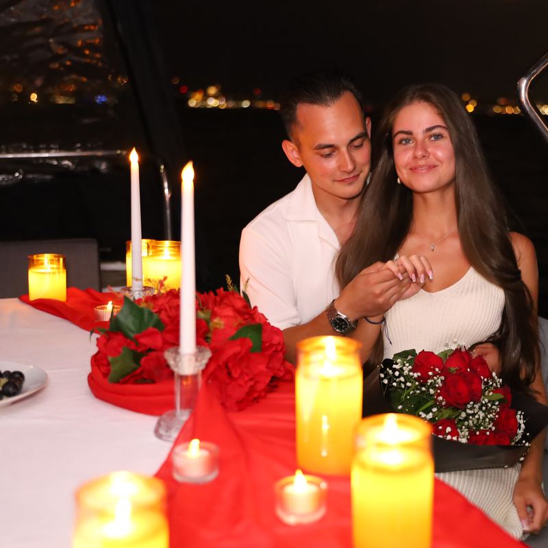 Couple with roses and the engagement ring by candlelight