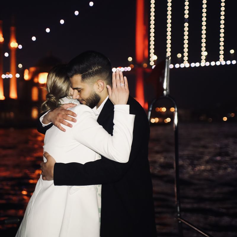 An embrace after the proposal, with the lights of the Bosphorus Bridge behind
